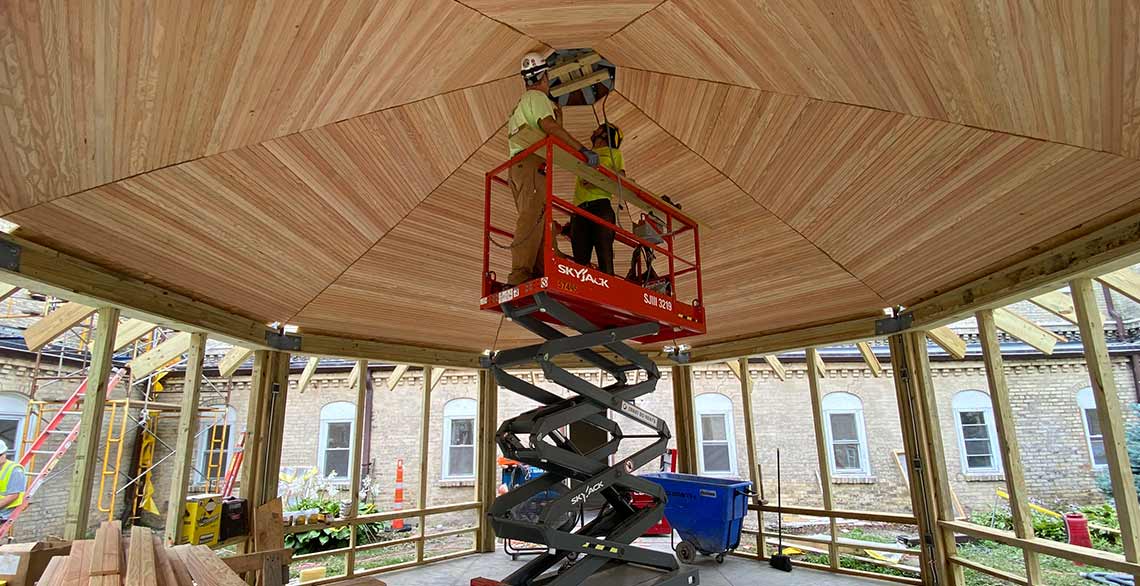 Workers using a skyjack to work on the ceiling of the gazebo in the courtyard of St. Francis of Assisi Monastery.