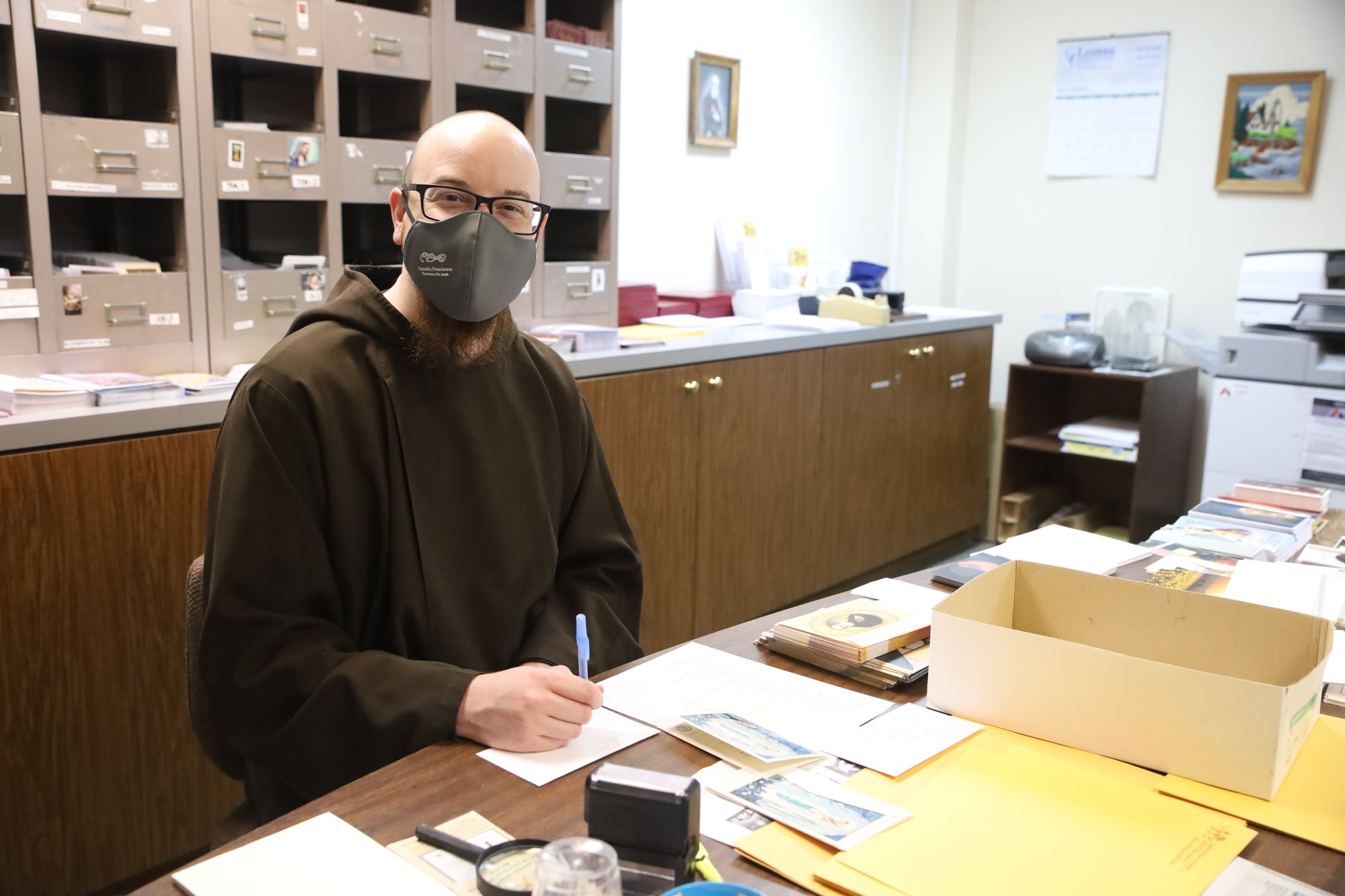 Photograph of Br. Nick Blattner preparing Solanus Mission Association cards and folders.