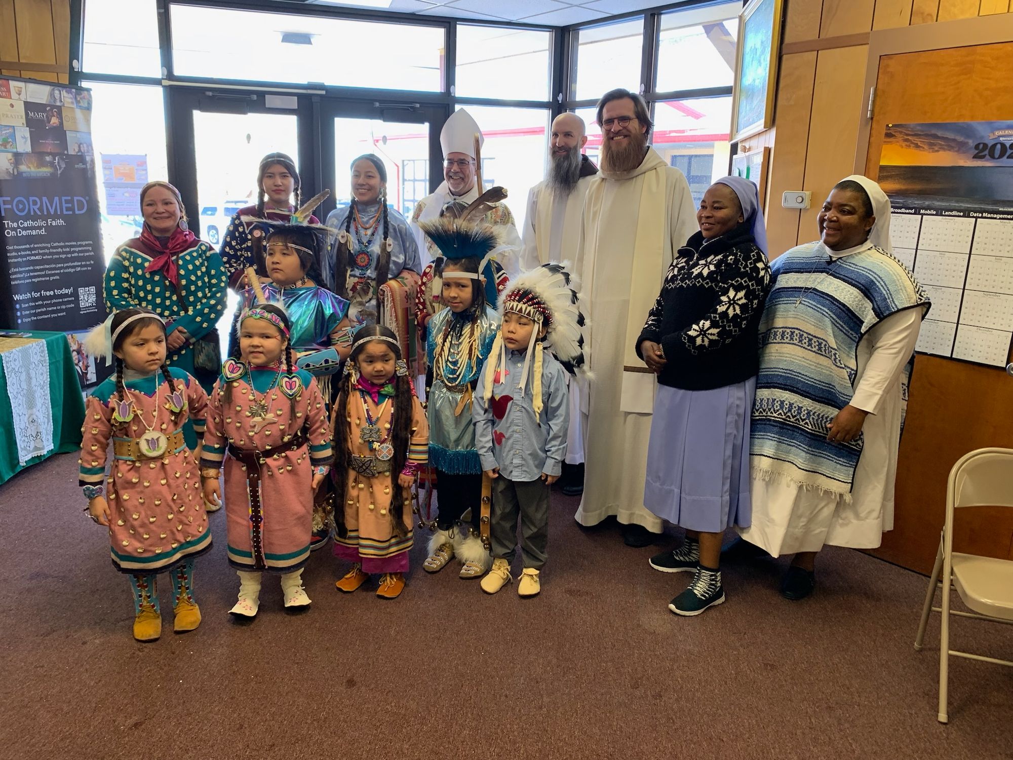 Bishop Warfel, Br. Mike Dorn and Br. Thomas Skowron along with parishioners and religious sisters in the vestibule after Mass.