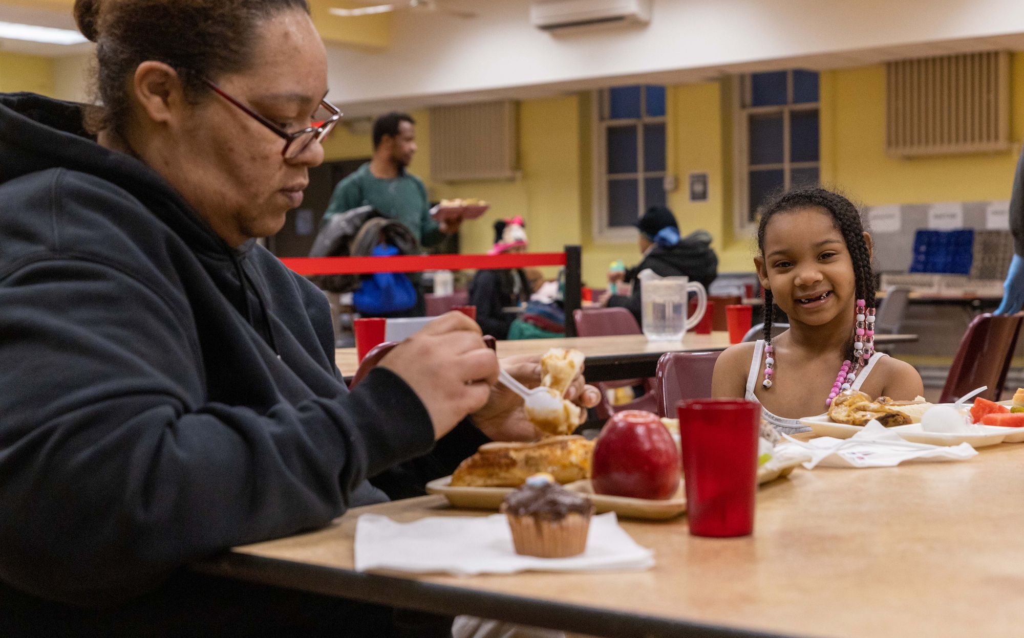 A mother and smiling daughter seated at a table eating dinner at St. Ben's. 