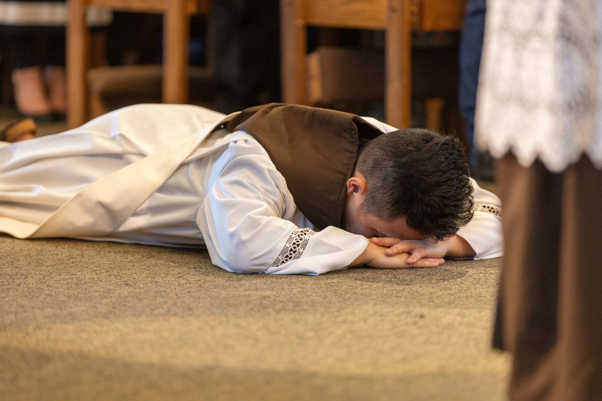 Interior photograph of Br. Truong Tien Dinh as he lies prostrate before the altar during his ordination.