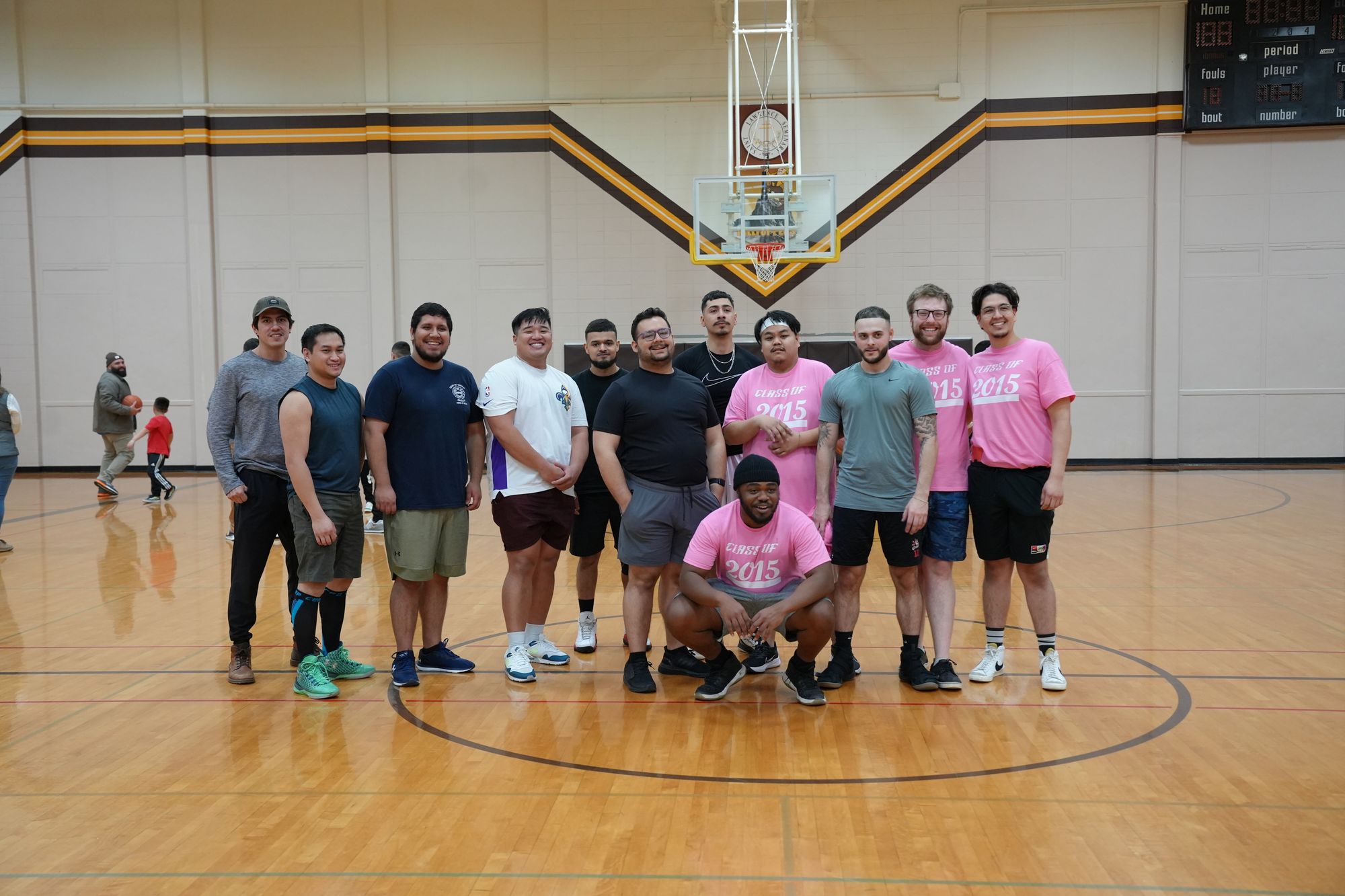 Alumni pose at center court of the gym during the 3-on-3 basketball tournament.