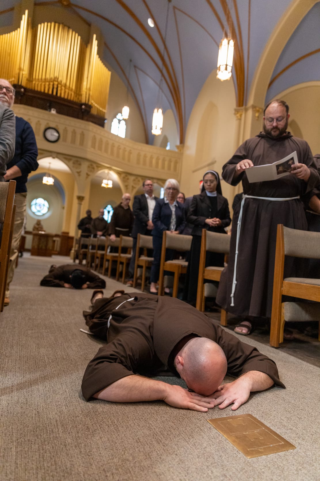 The newly-professed lie prostrate before the altar at St. Bonaventure.