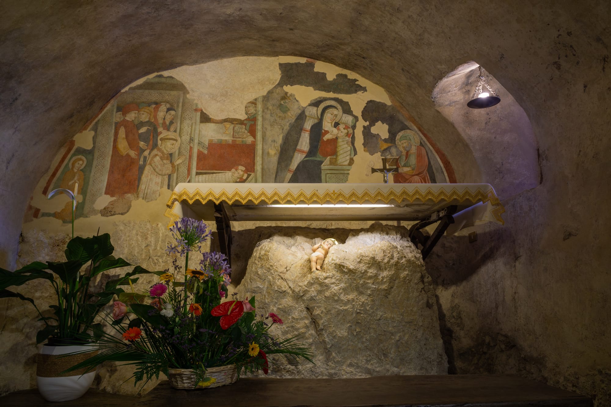 An altar inside the grotto of Greccio with a fresco depicting the first nativity scene from 1223.