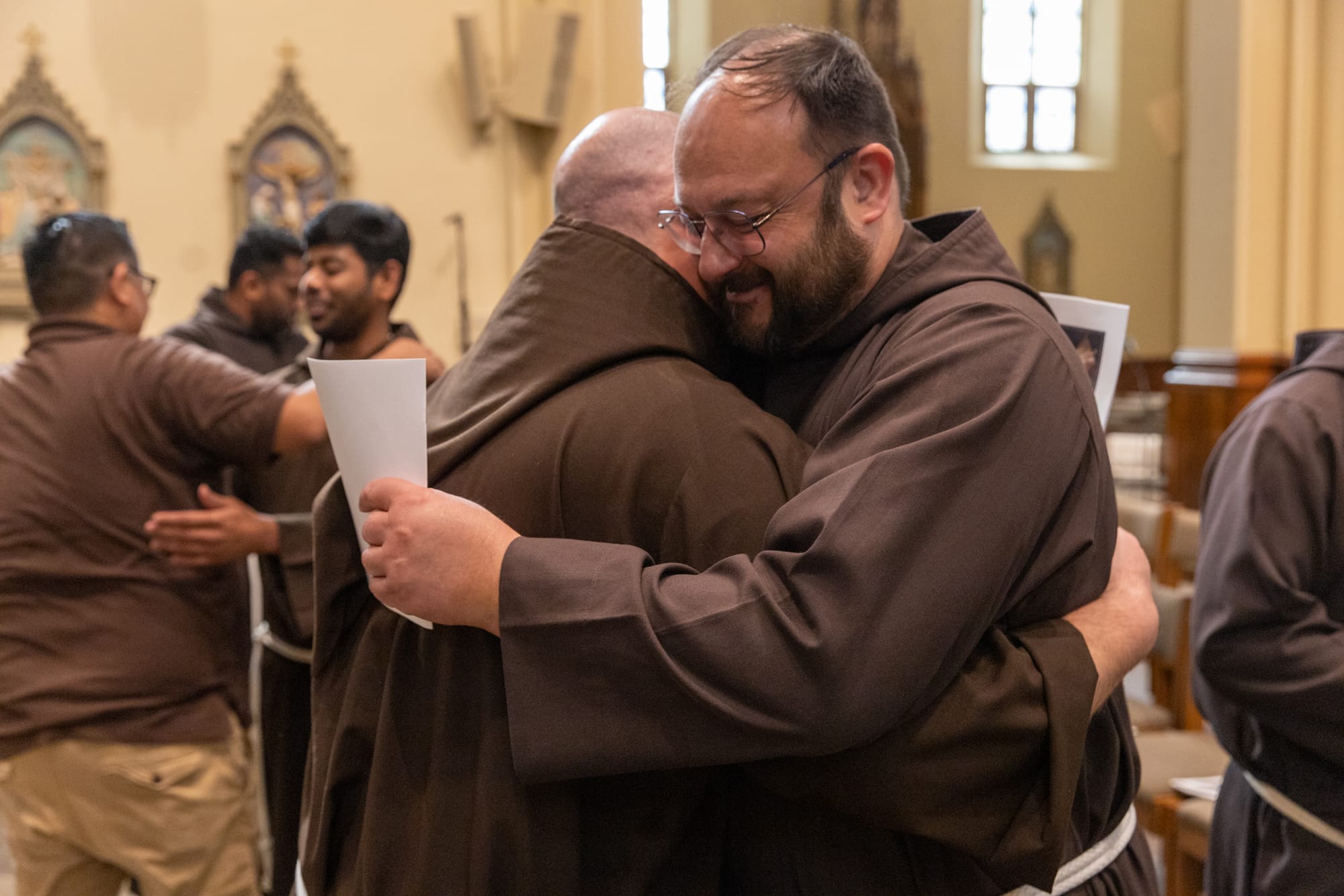 Friars share an embrace at the Profession of Vows in Detroit.