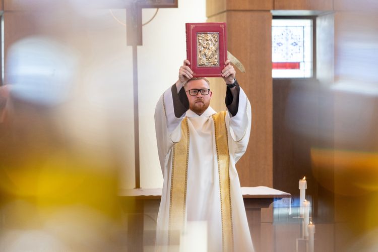 Br. Nathan Linton holds the book of the Gospels inside the Chapel at St. Xavier University during the triennial chapter.